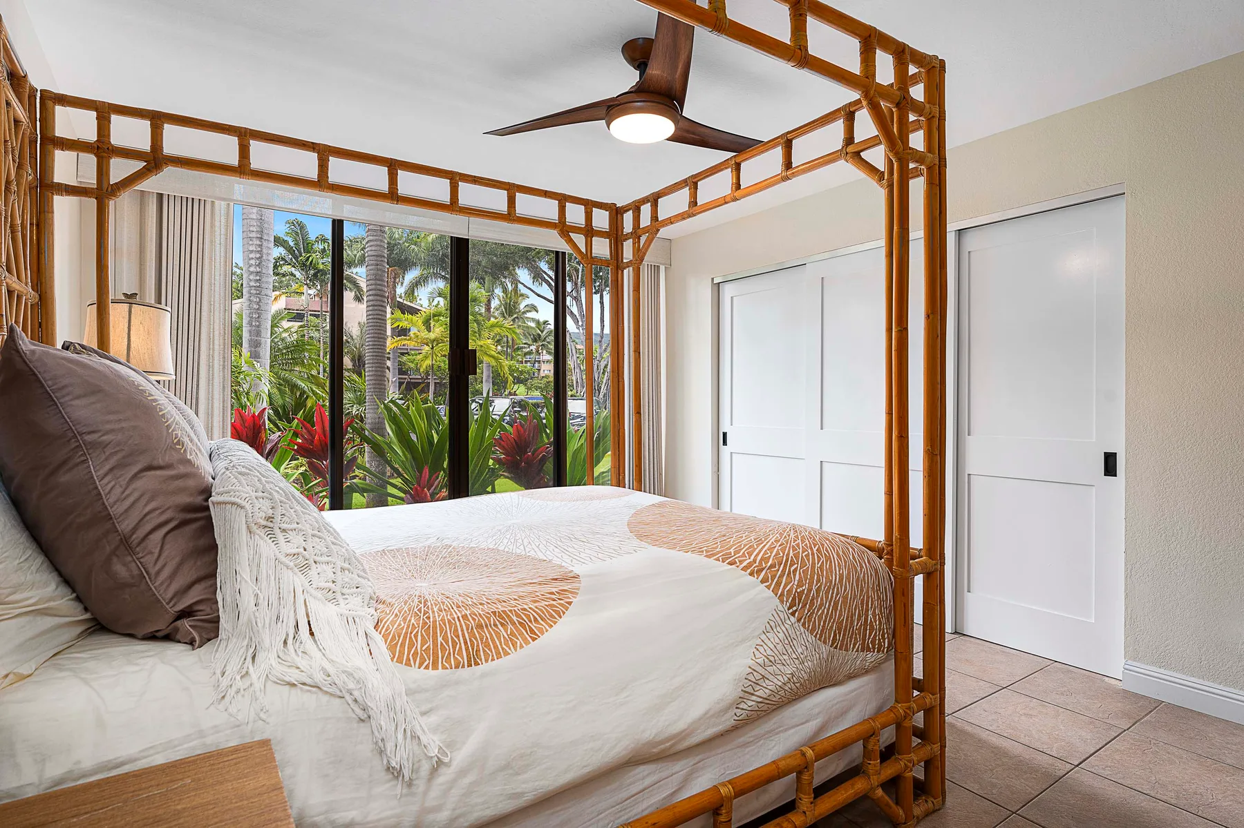 Dormitorio con una cama bajo un dosel de madera y grandes ventanas con vistas a la vegetación.