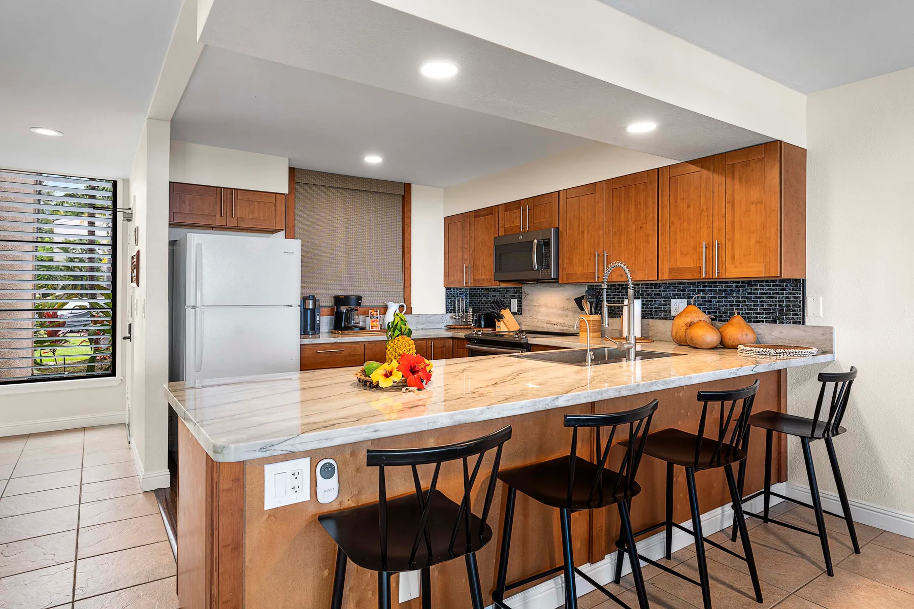 Una cocina con una isla grande, asientos de barra y gabinetes de madera.
