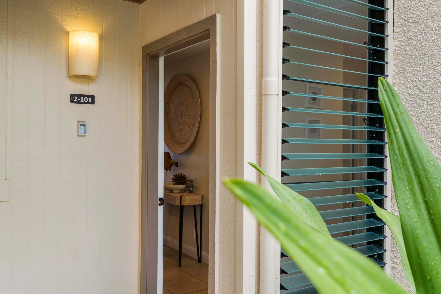Una entrada da paso a una habitación con una mesita y decoración en la pared.