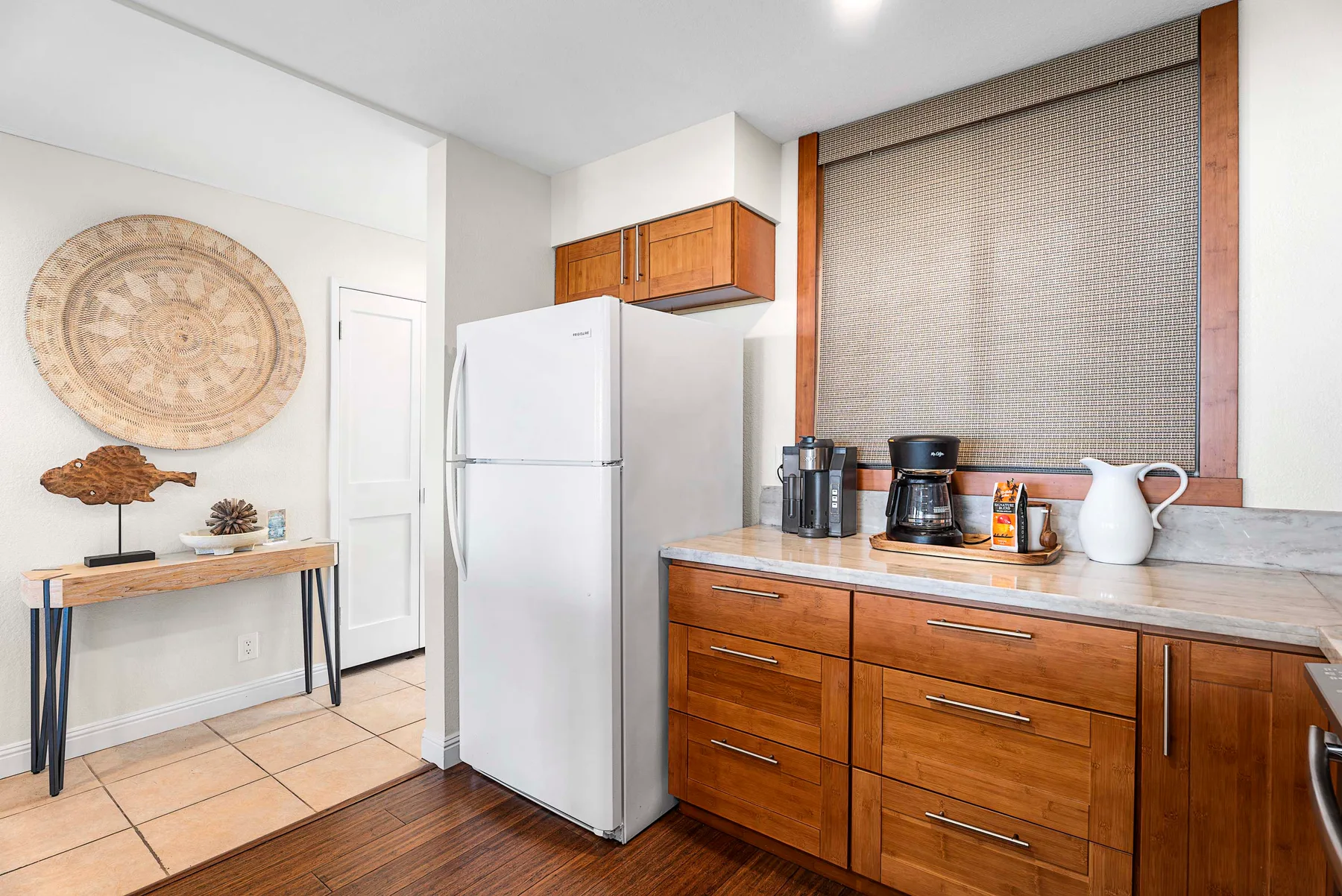 Una cocina compacta con gabinetes de madera, un refrigerador y una cafetera sobre la encimera.