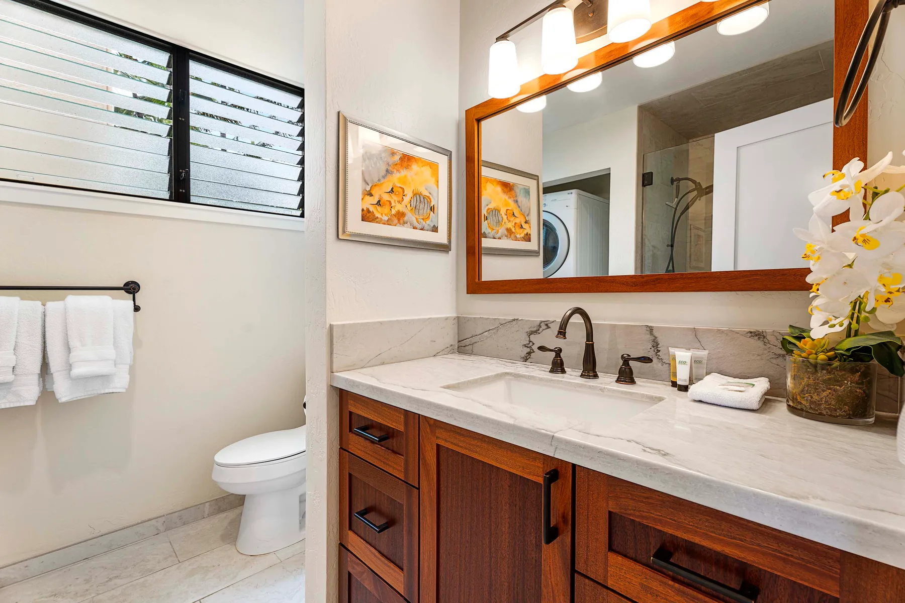Un tocador de baño con un espejo grande, lavabo y muebles de madera.