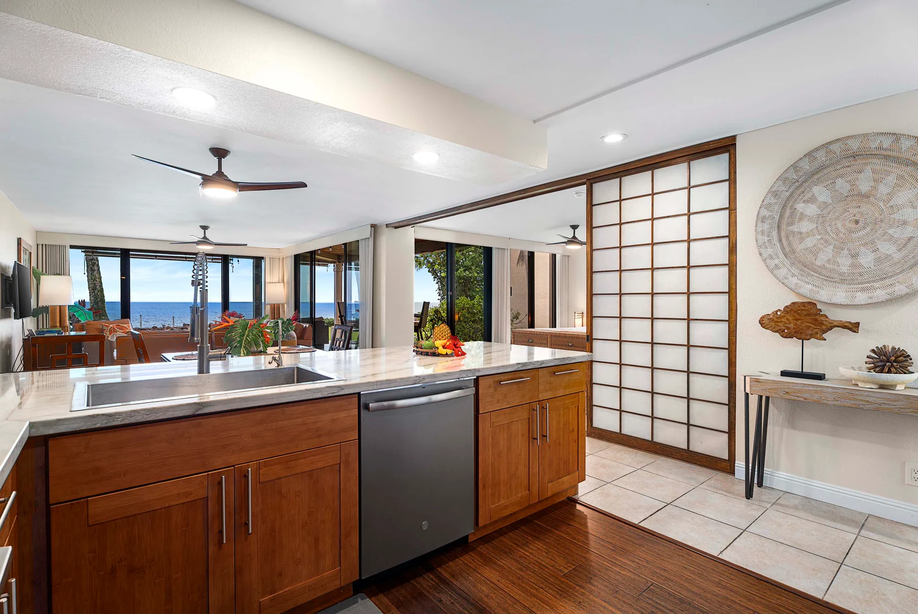 Una cocina se abre a un comedor con grandes ventanales con vistas al agua.