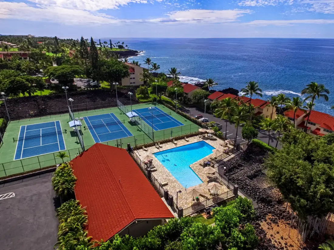 Un complejo costero con canchas de tenis y una piscina junto al océano.