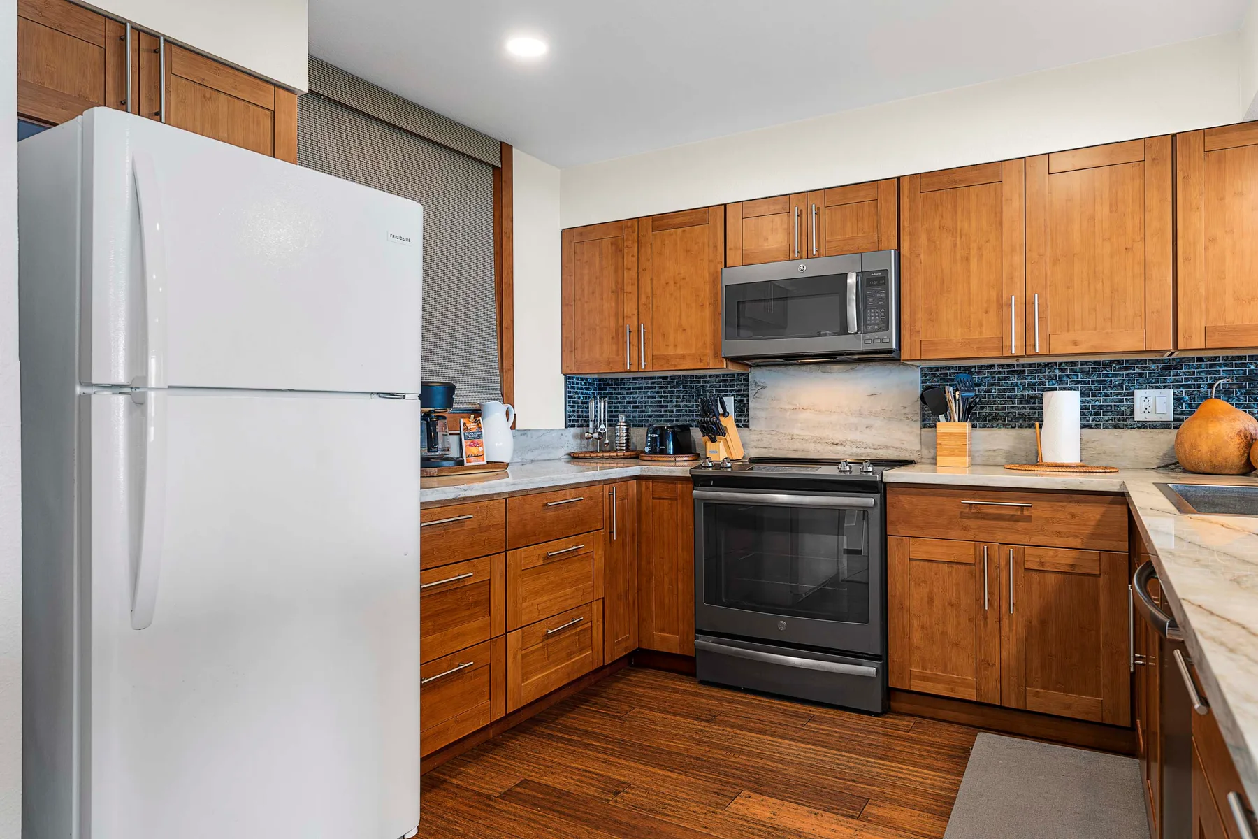 Una cocina con gabinetes de madera, un refrigerador y una estufa central.