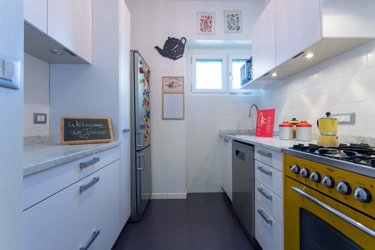 A bright kitchen with white cabinets, a refrigerator, and a yellow stove.