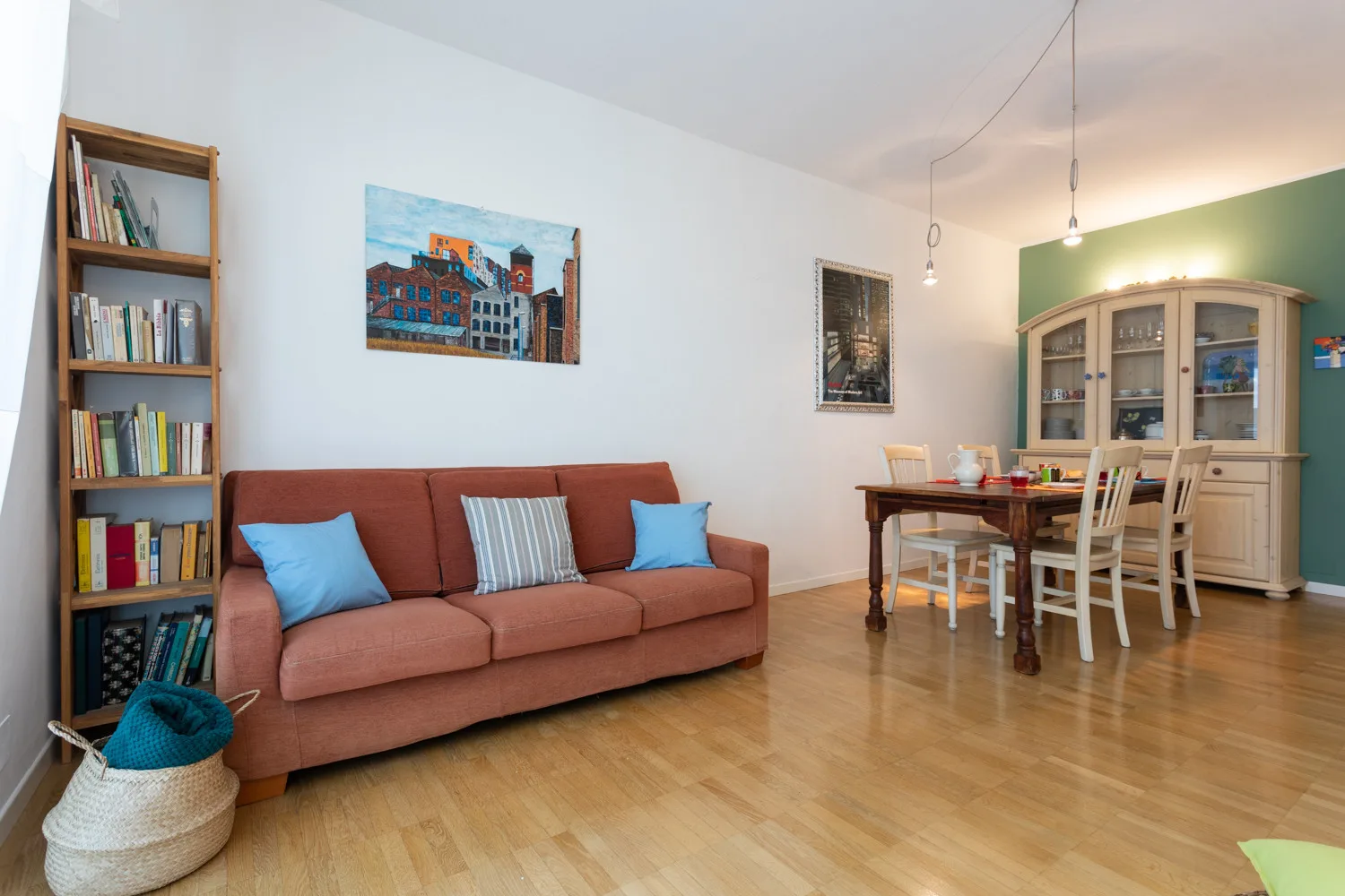 Una sala de estar y comedor con sofá, estantería y mesa de comedor.