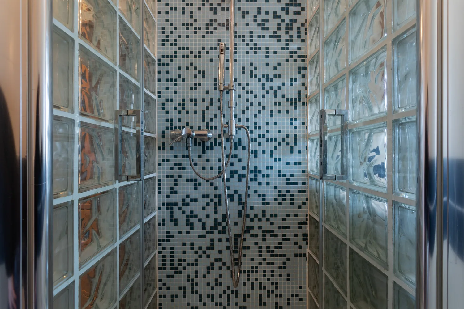 A tiled shower with glass-block walls and a wall-mounted shower fixture.