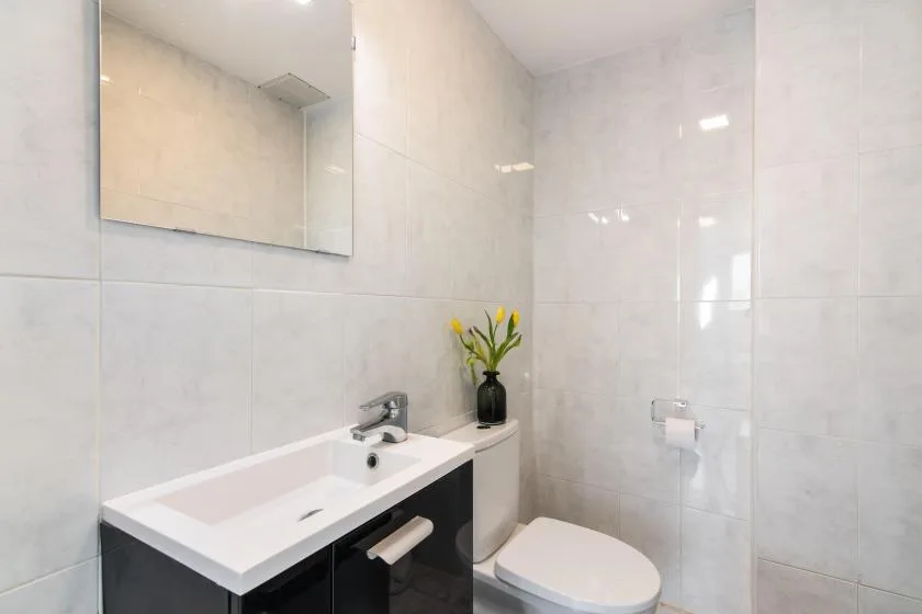 A tiled bathroom with a sink, mirror, and toilet.