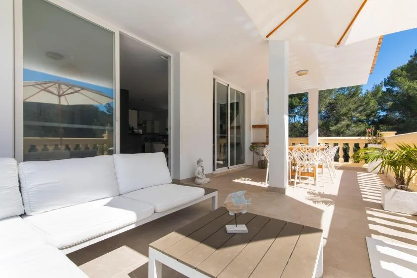 A bright covered patio with outdoor seating and a low table.