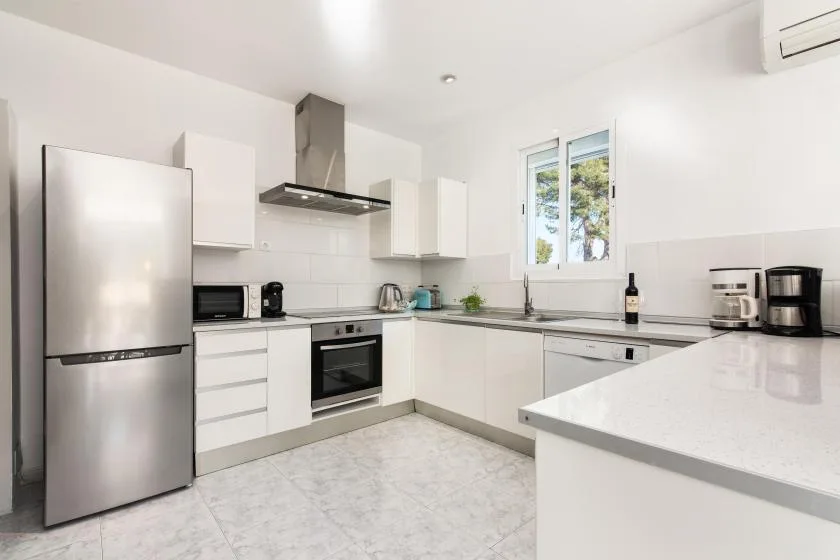 A bright kitchen with white cabinets and stainless steel appliances.