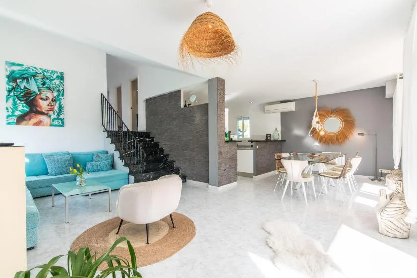 A bright open-plan living and dining room with a turquoise seating area and dining table.