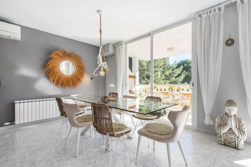 A bright dining area with a glass table and an open view to the terrace.