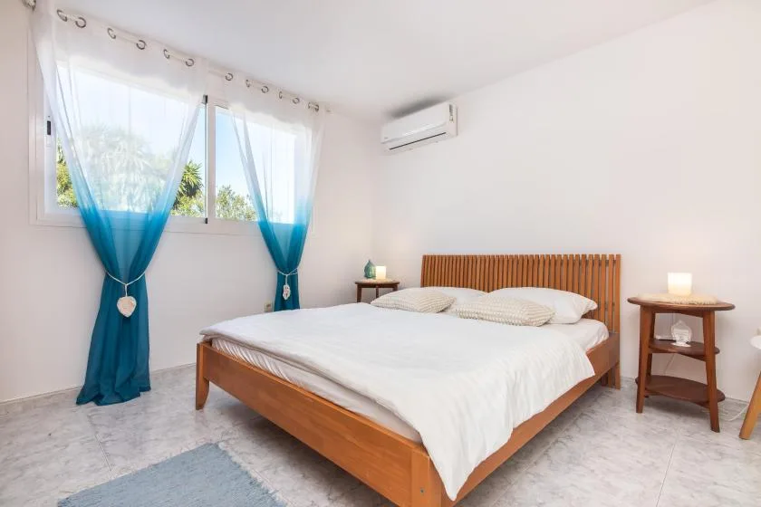 A bedroom with a wooden bed, white bedding, and blue curtains.
