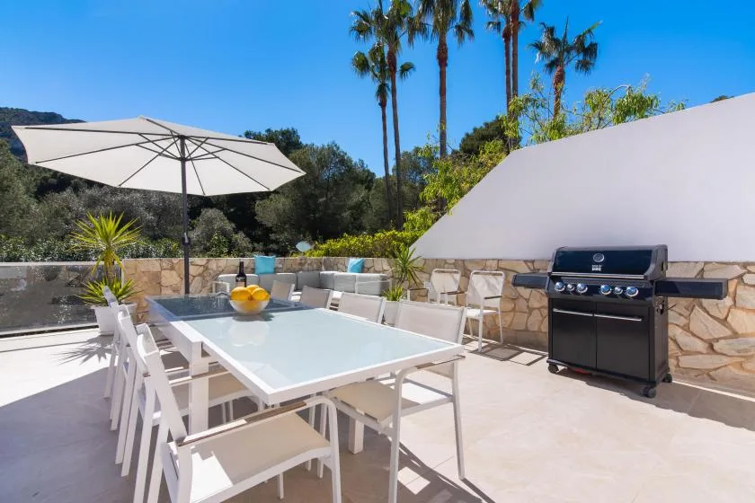 An outdoor dining area with a table, umbrella, and grill.
