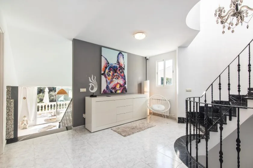 A bright entry hall features a white console beneath colorful wall art.