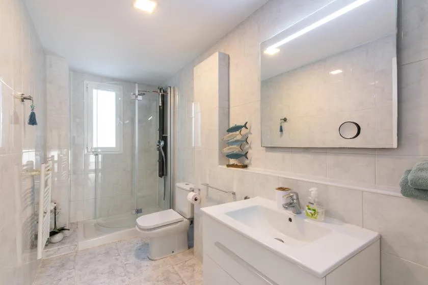 A bright bathroom with a glass shower and a sink beneath a large mirror.