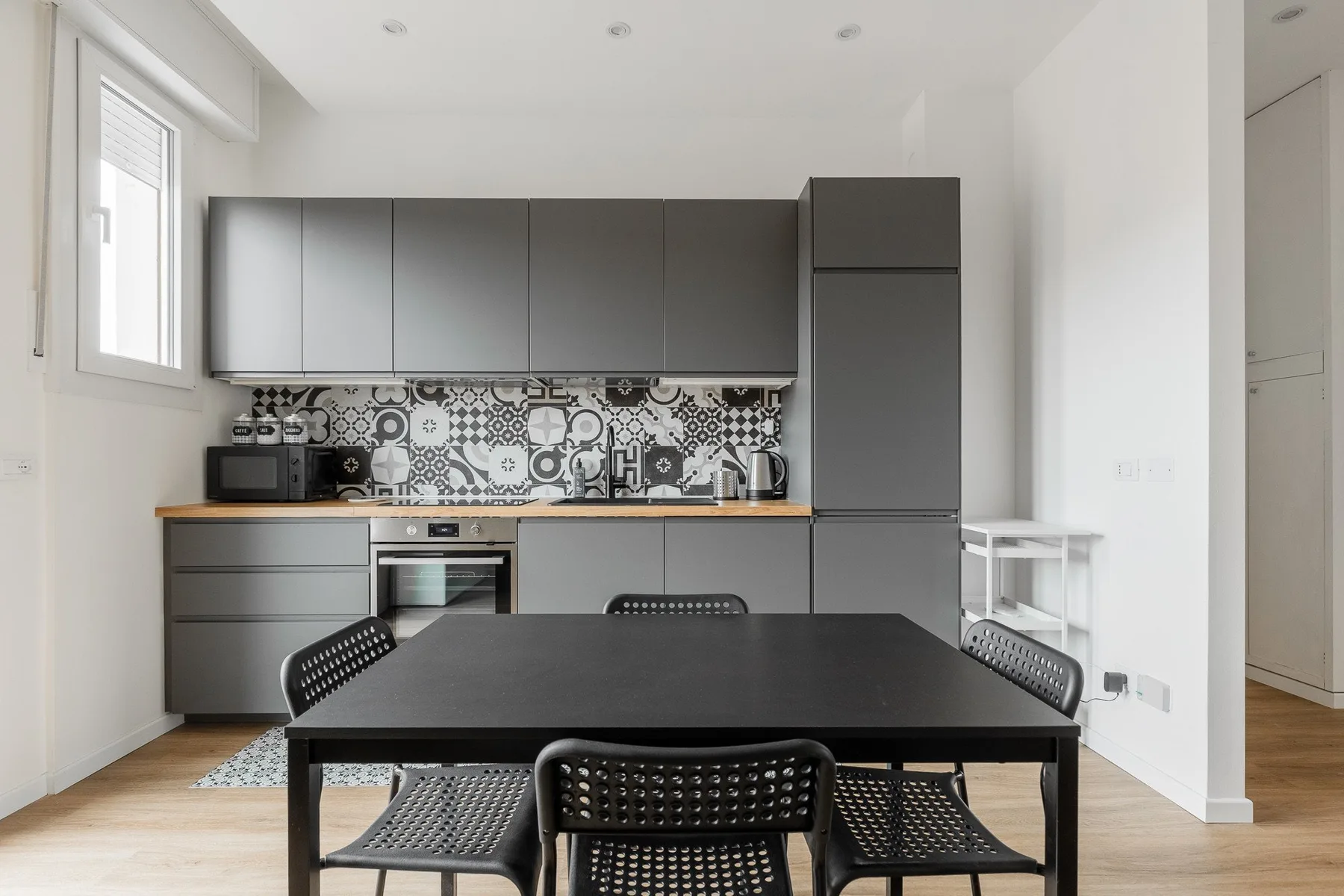 Una cocina moderna con gabinetes oscuros y una mesa de comedor en primer plano.