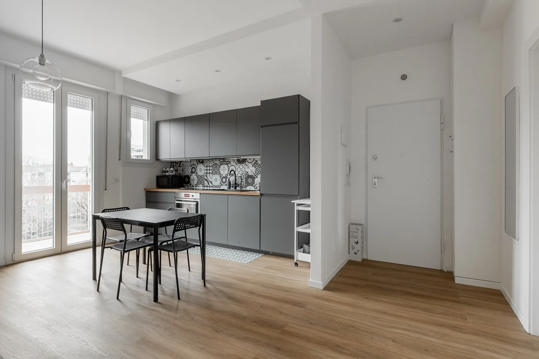 Una cocina abierta y luminosa con una mesa de comedor junto a ventanas altas.