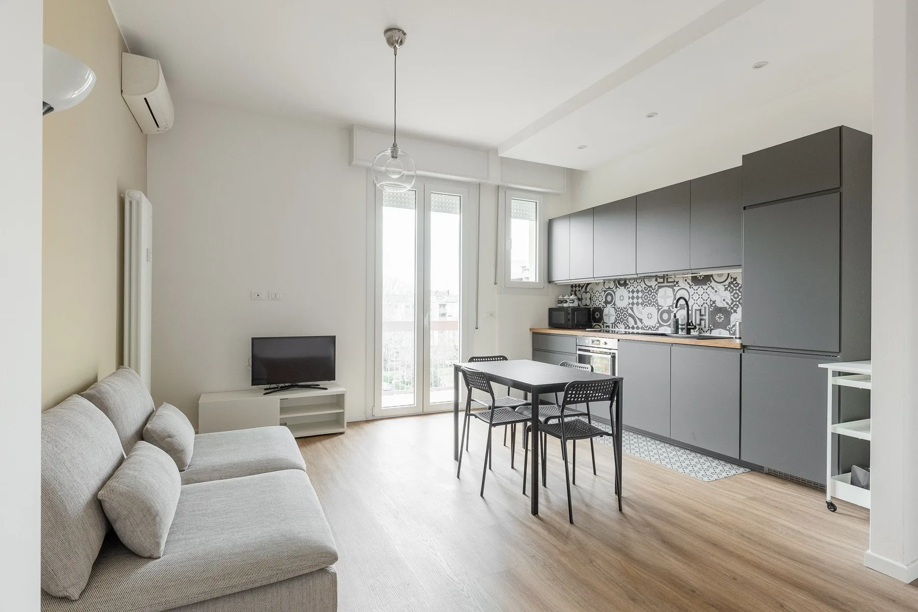 Una luminosa sala de estar y comedor diáfana con sofá y cocina integrada.