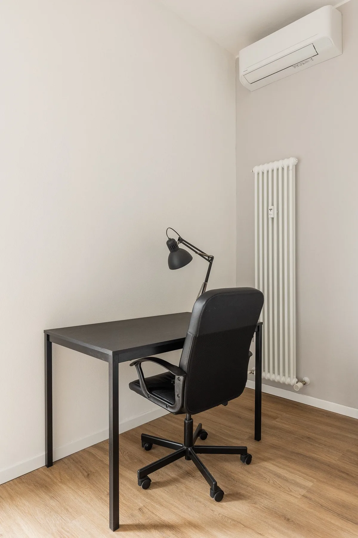 Un espacio de trabajo sencillo con escritorio, silla de oficina y lámpara de escritorio.