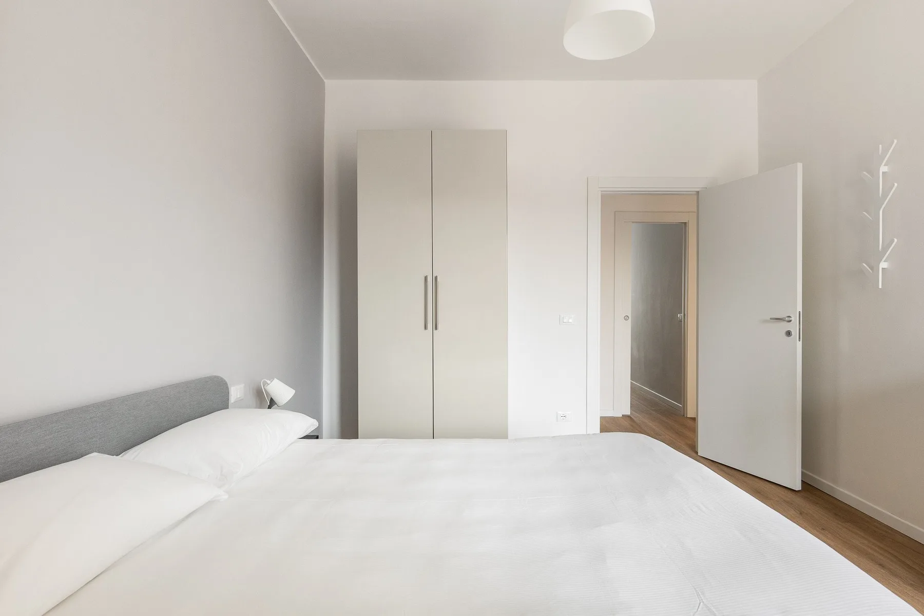 Un dormitorio luminoso con una cama, un armario y una puerta abierta.