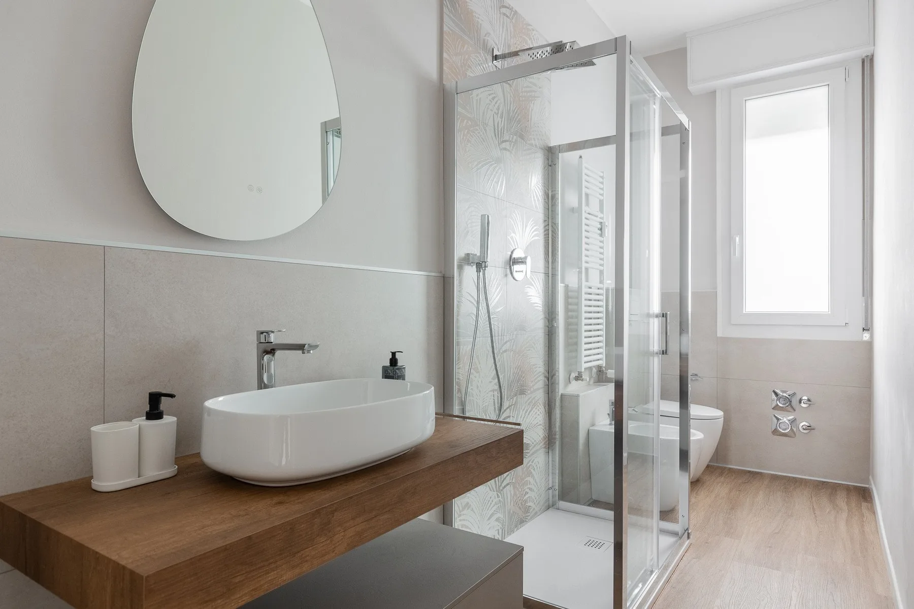 Un baño luminoso con lavabo sobre encimera y ducha de vidrio.