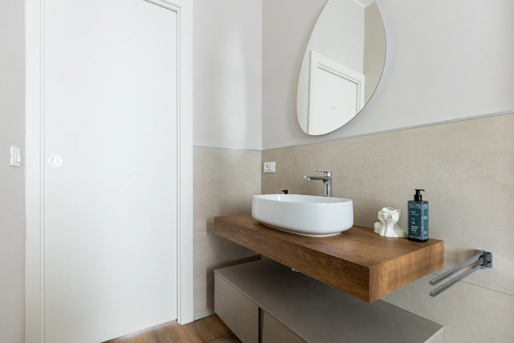 Un lavabo de baño con una pila blanca, espejo de pared y grifo.