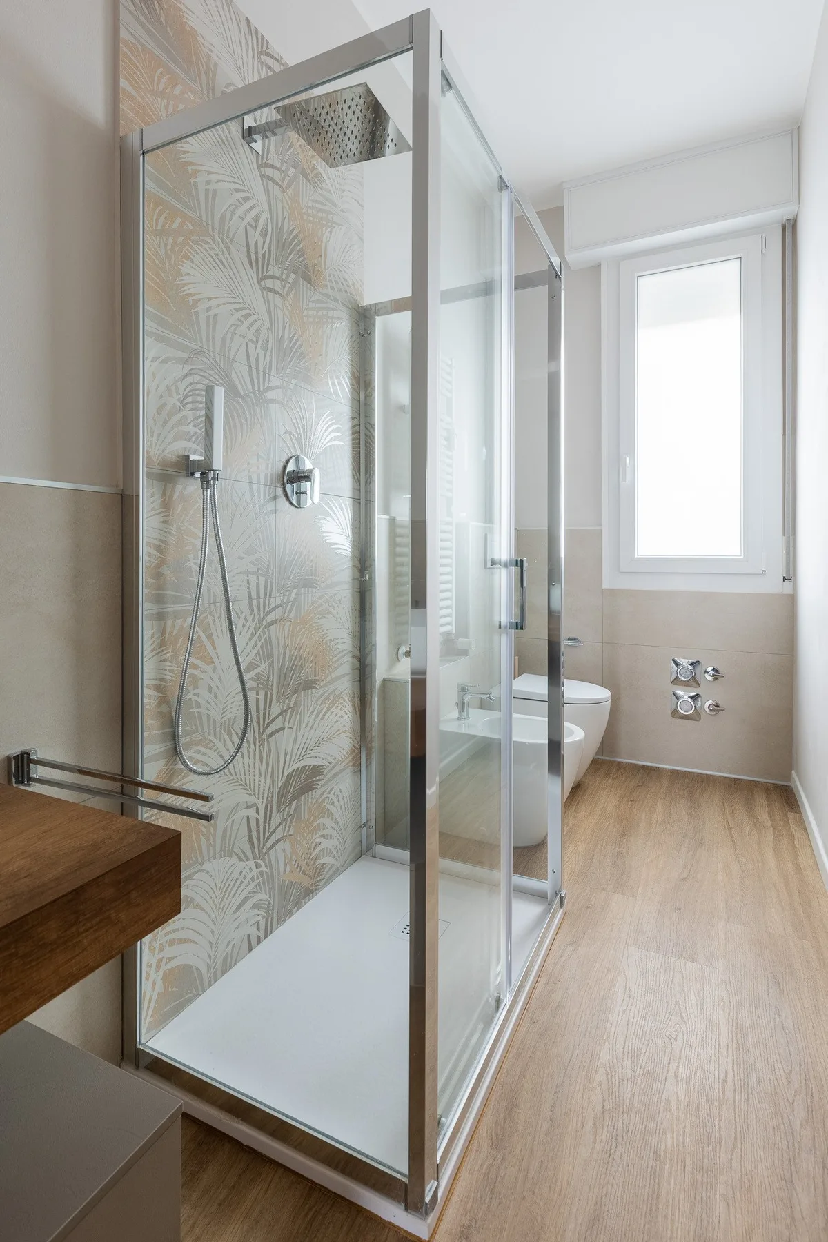 Un baño con una ducha de vidrio y una ventana.