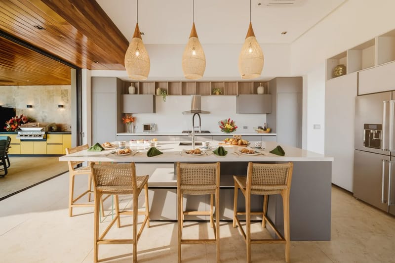 Casa Ama · 35. This bright kitchen features a large island with seating, modern appliances, and wide retractable doors opening to an outdoor grilling station.
