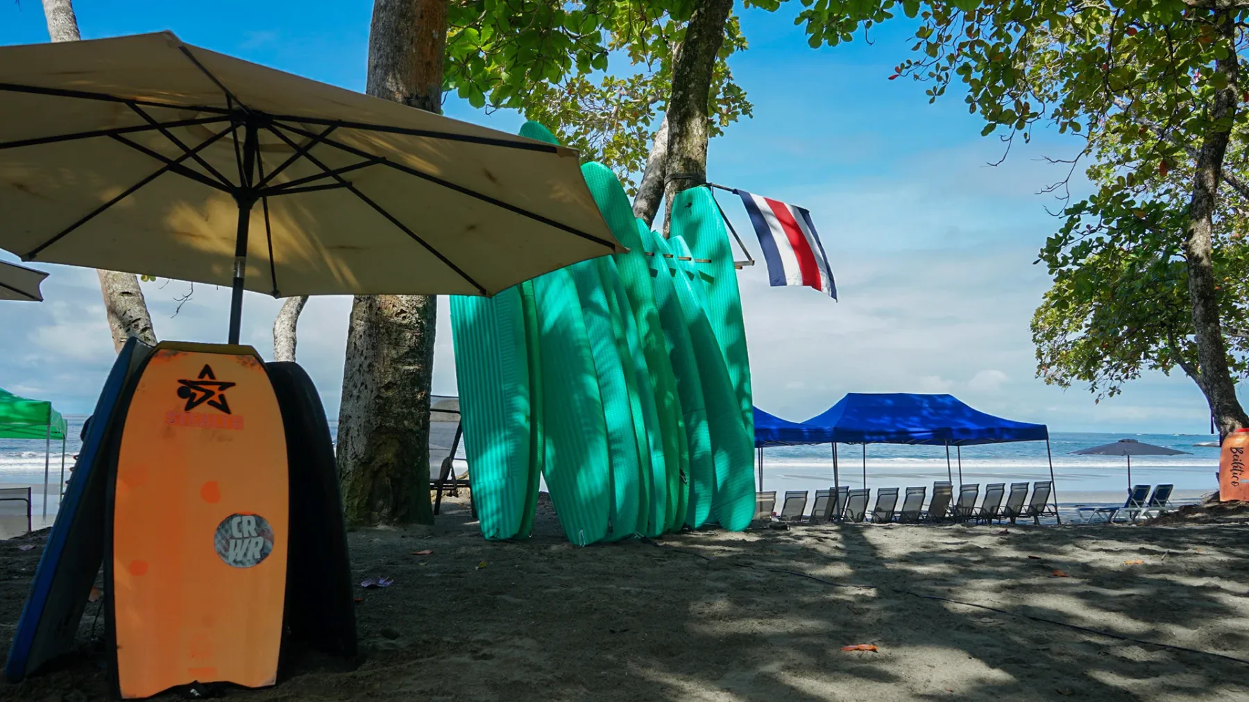 Casa Ama · 49. This outdoor beach club offers shaded lounge chairs under umbrellas and a large blue canopy, along with a rack of surfboards, all facing the open ocean.