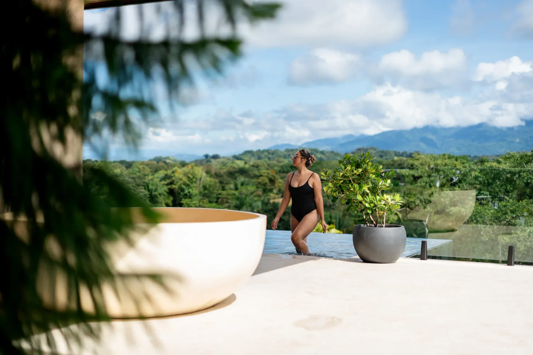 Casa Ama · 34. The outdoor infinity pool overlooks an expansive vista of tropical forests and distant mountains under a bright, cloudy sky.