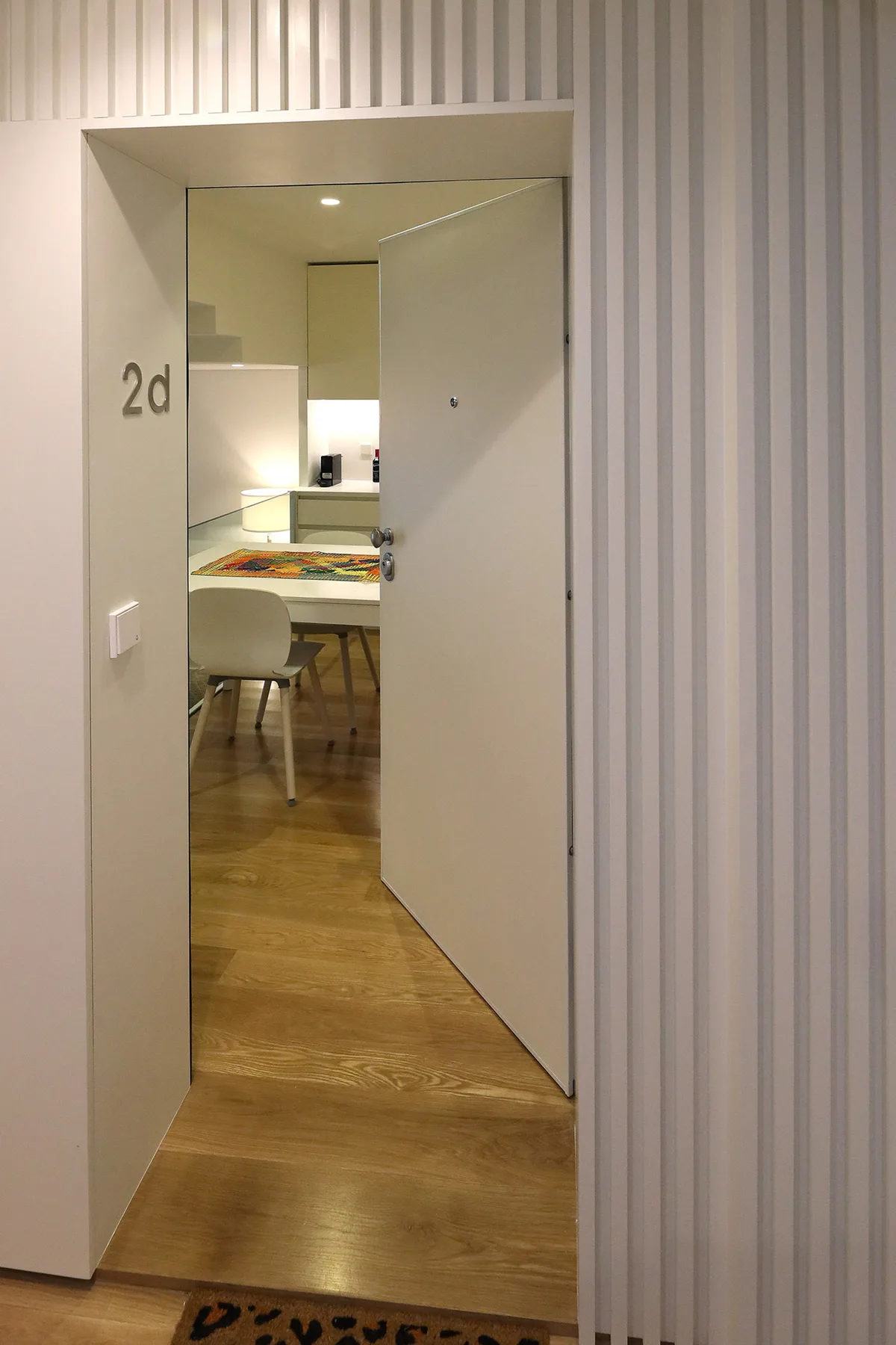 Una puerta abierta deja ver una mesa de comedor y asientos en una habitación interior.