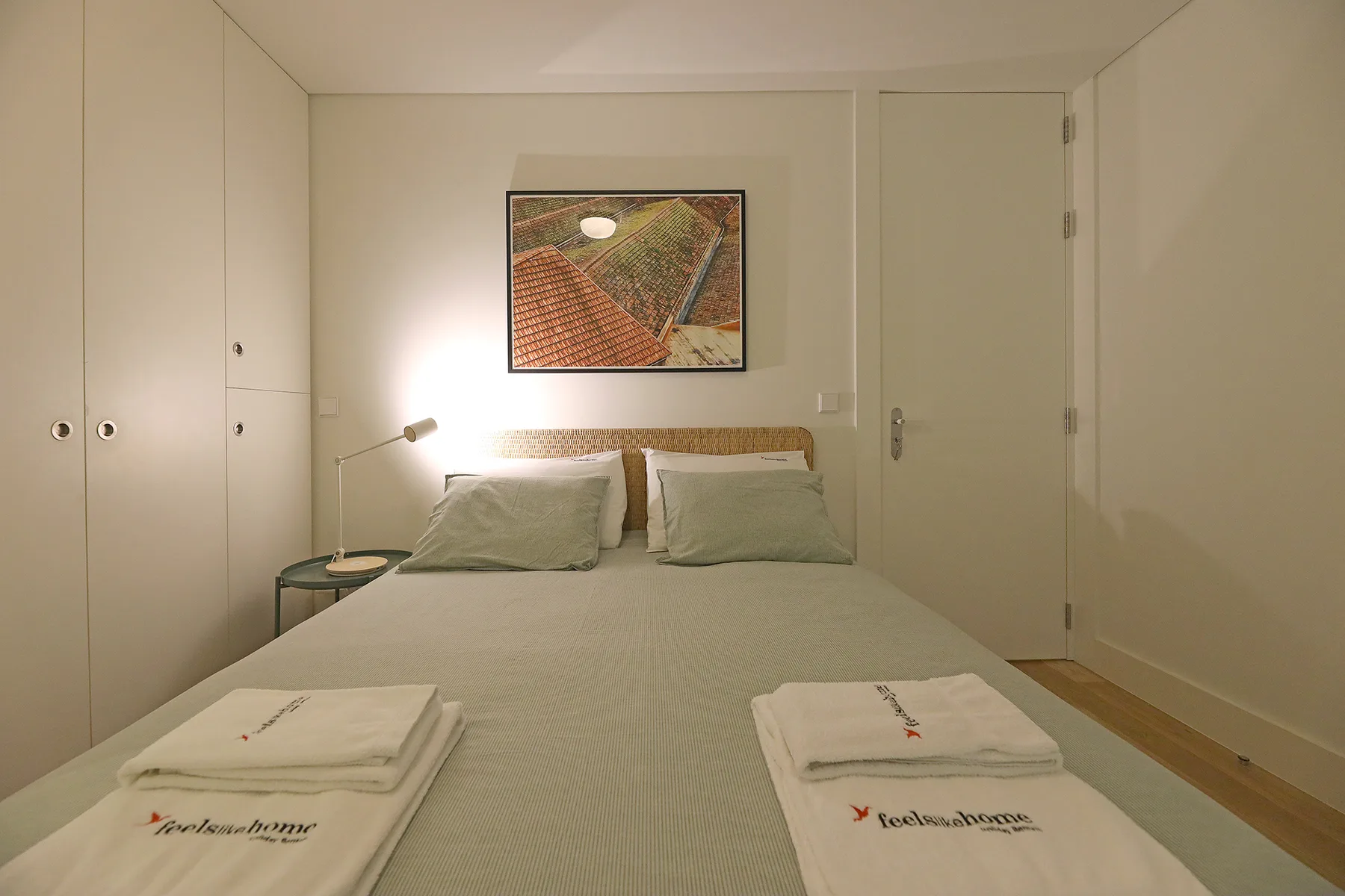 Dormitorio con cama doble, mesita de noche y un cuadro enmarcado.