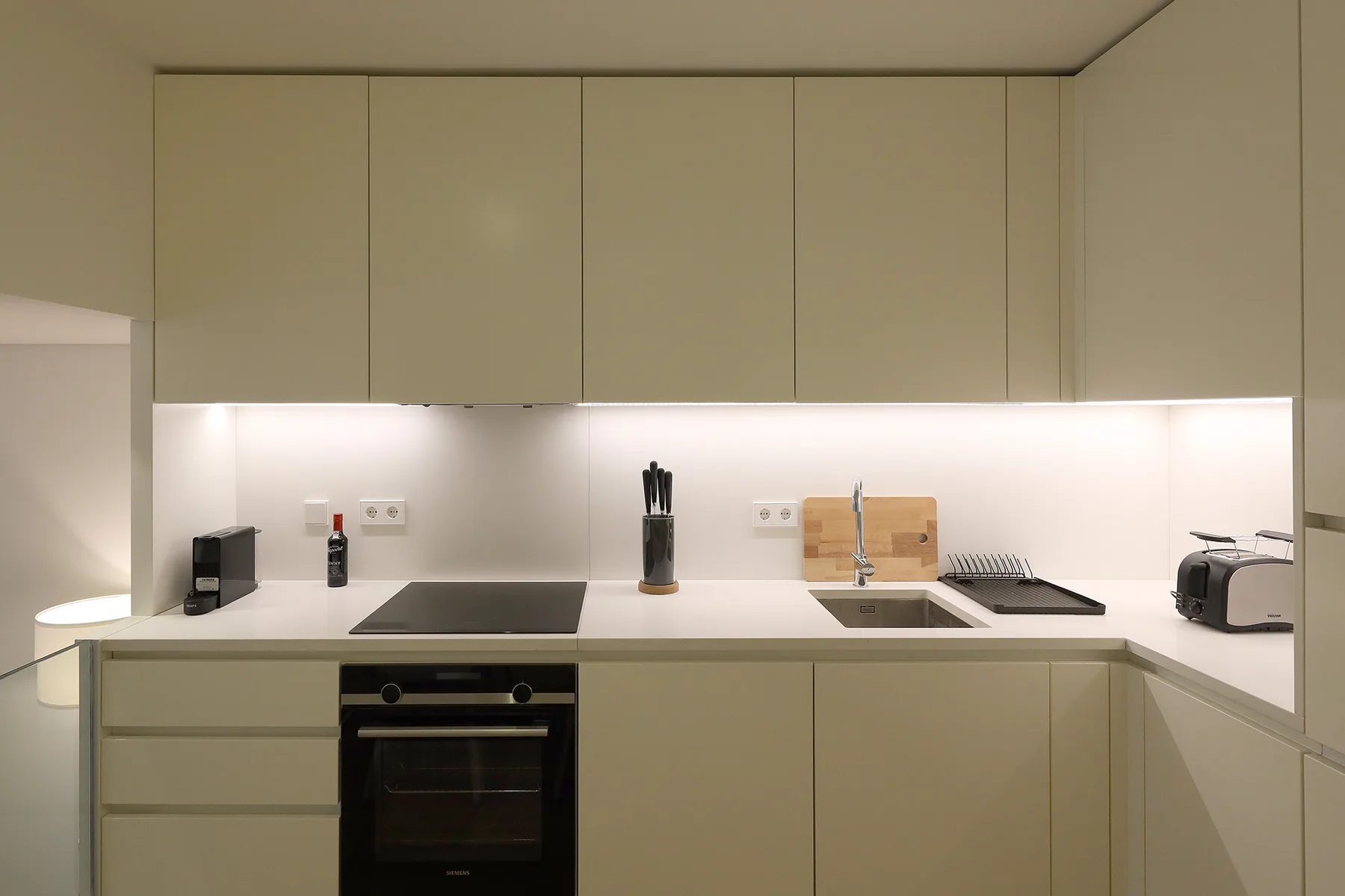 Una cocina moderna con gabinetes claros, una placa de cocina y un horno.