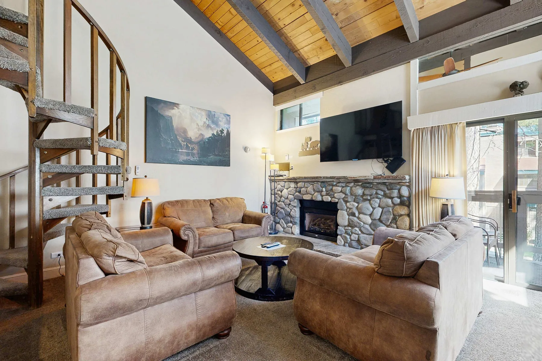 Una sala de estar con asientos alrededor de una chimenea de piedra y un televisor.
