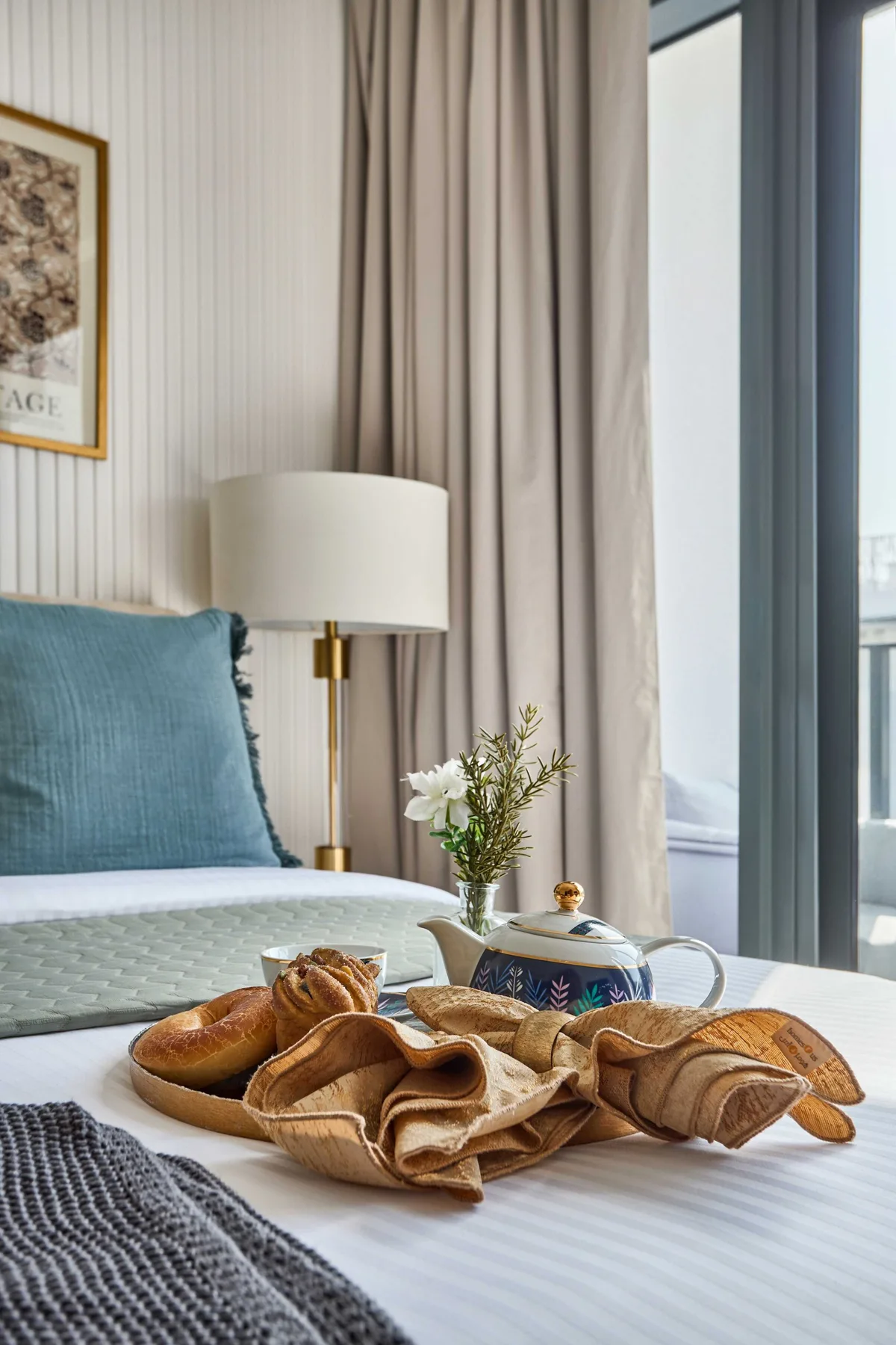 Un rincón de dormitorio con una cama, una lámpara y el desayuno en una bandeja.
