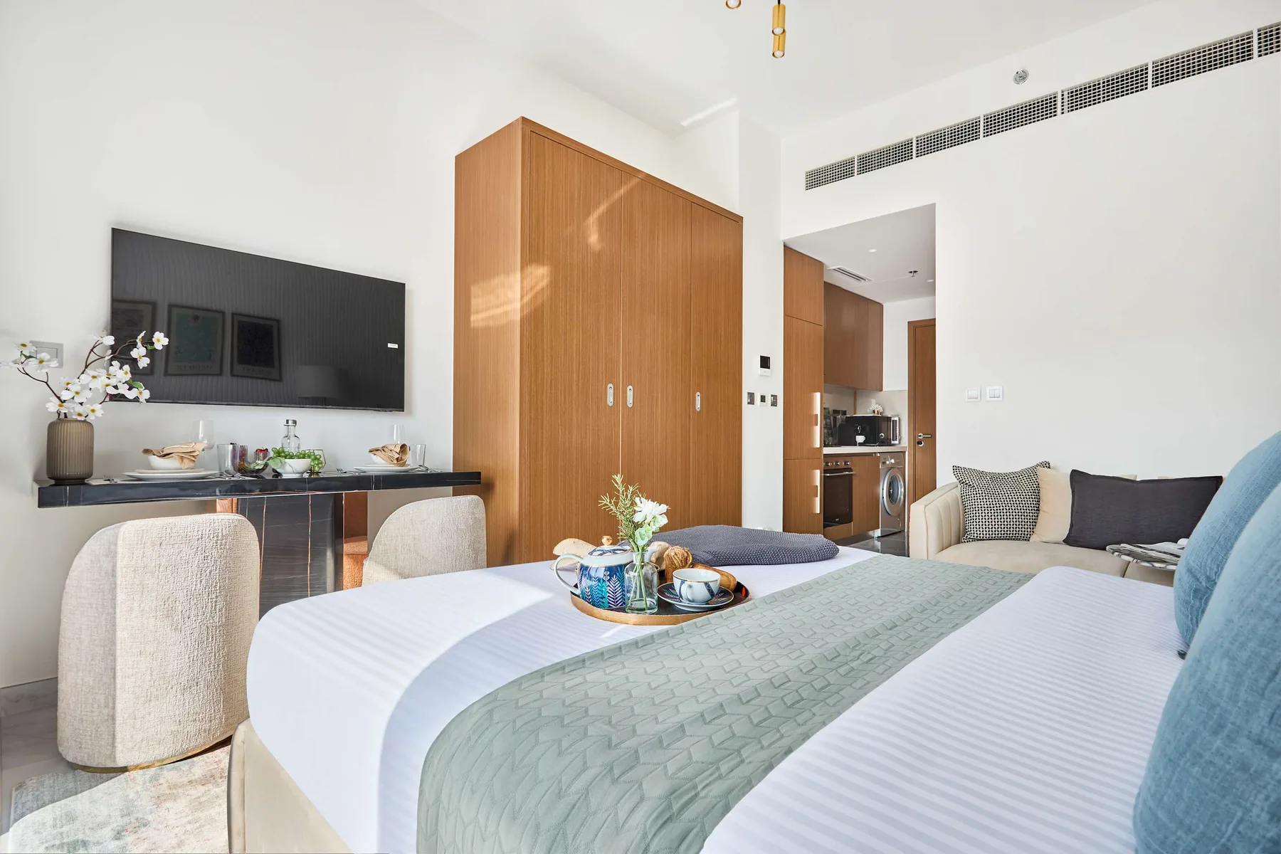 Un dormitorio luminoso con una cama bien arreglada y una pequeña zona de comedor.