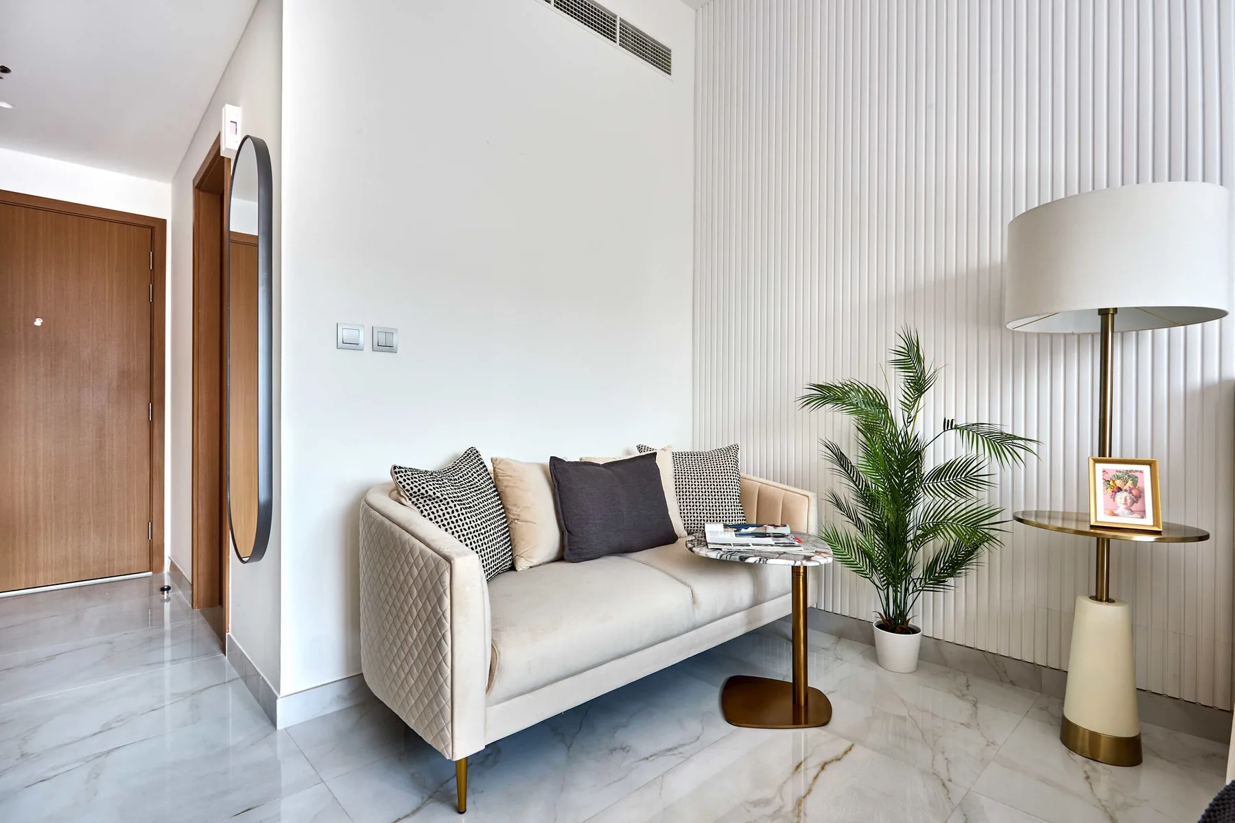Una luminosa sala de estar con sofá crema, mesa auxiliar y palmera en maceta.