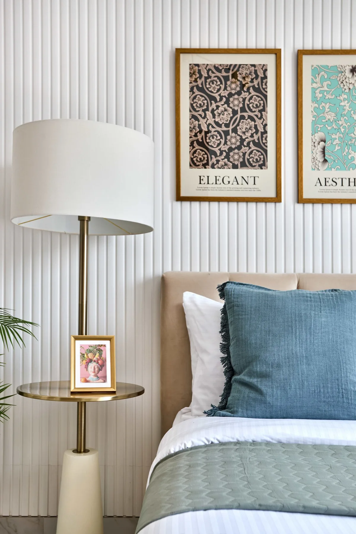 Un dormitorio con una cama, almohadas azules y cuadros en la pared.
