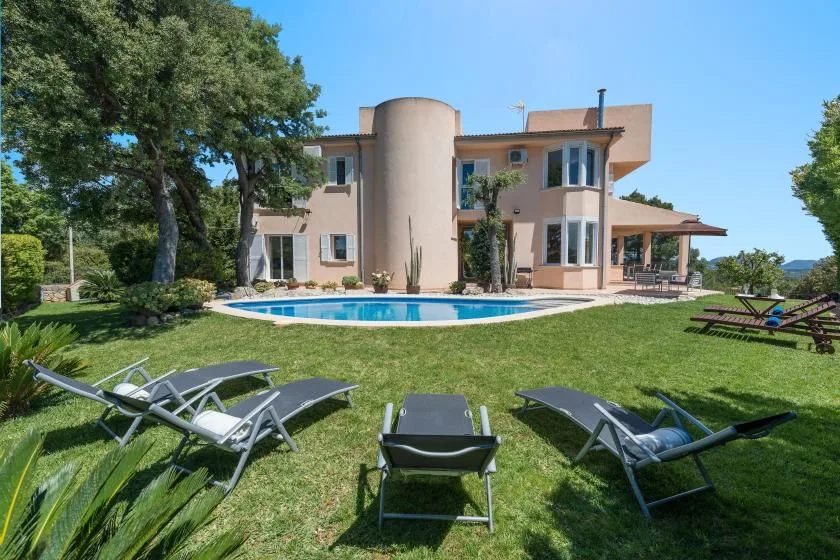 Una casa moderna da a una piscina curva y un césped.