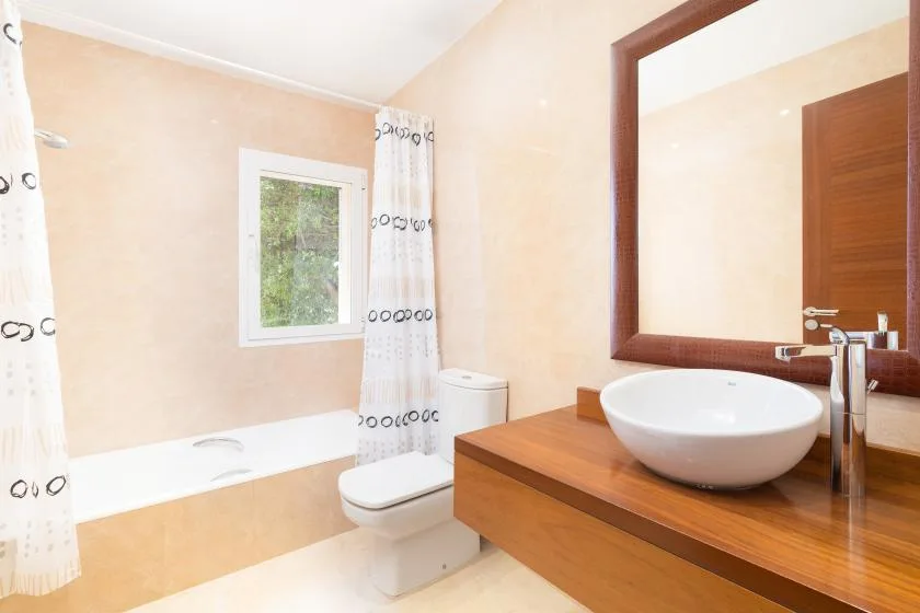 Un baño con bañera, inodoro y lavabo bajo un espejo grande.