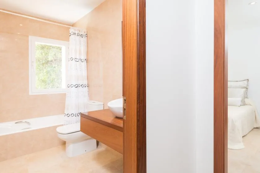 Un baño con bañera y lavabo, junto a un dormitorio.