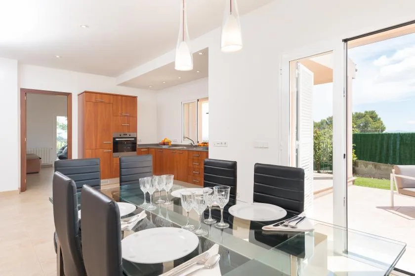 Comedor con una mesa de cristal y una cocina abierta.