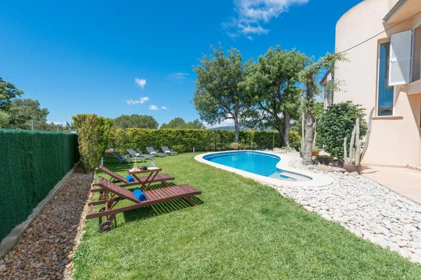 Un jardín con piscina, césped y asientos al aire libre.