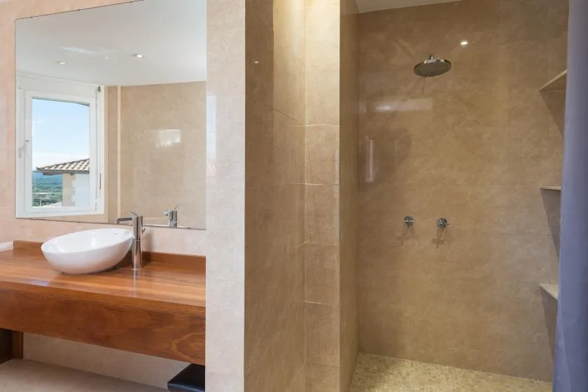 Un mueble de baño con lavabo está junto a una ducha revestida de azulejos.