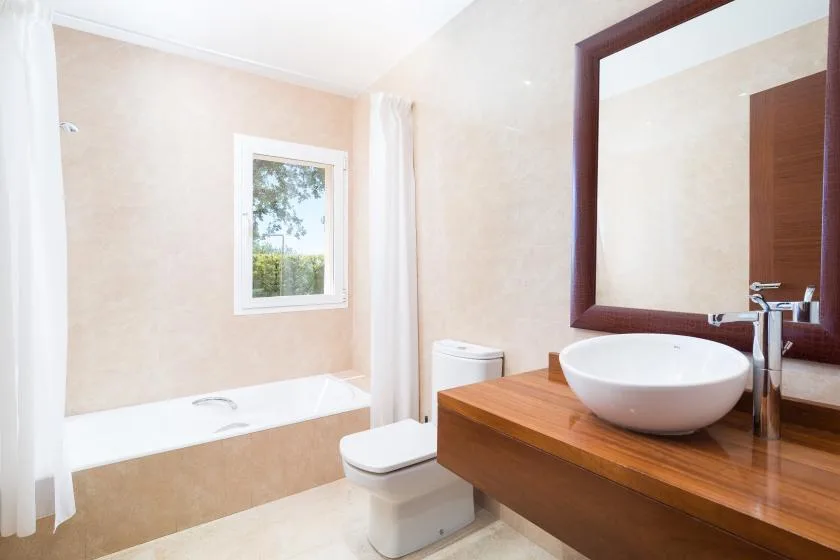 Un baño con bañera, inodoro y lavabo bajo un espejo grande.