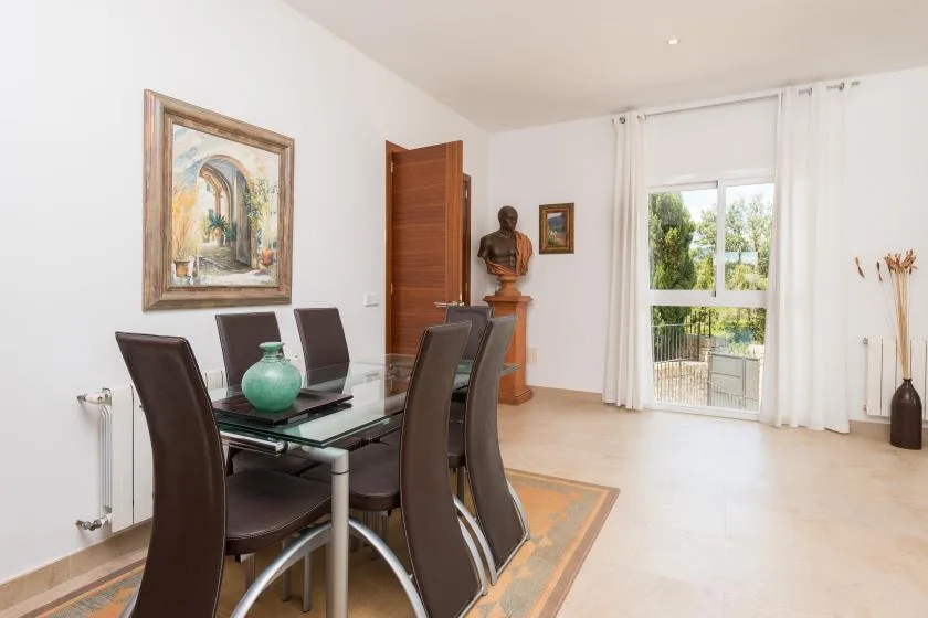 Un comedor con una mesa de vidrio y sillas junto a una ventana luminosa.