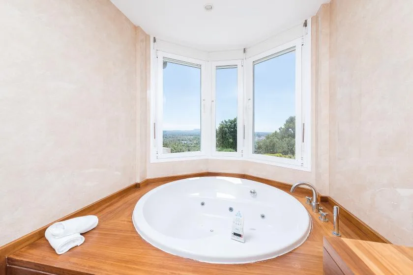 Un baño cuenta con una amplia bañera ovalada bajo una ventana mirador.