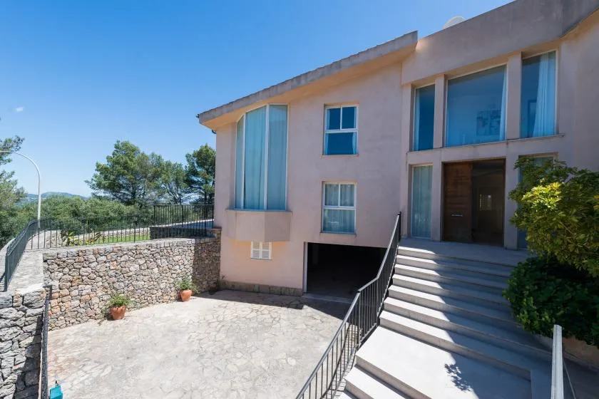 Entrada de un edificio moderno con amplios escalones y un patio pavimentado.