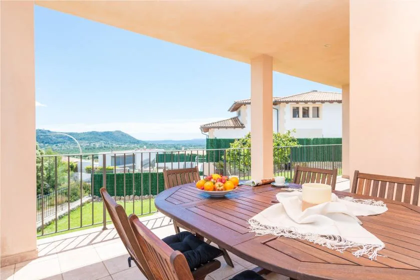 Una zona de comedor exterior cubierta con una mesa de madera y vistas a colinas verdes.